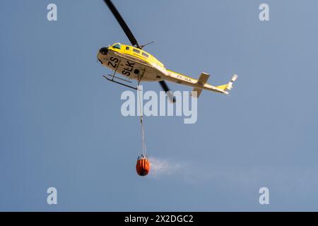 Arbeiten an einem feuergelben Nothubschrauber, der bambi-Wasserkübel zu einem Brandort in Kapstadt Südafrika transportiert Stockfoto