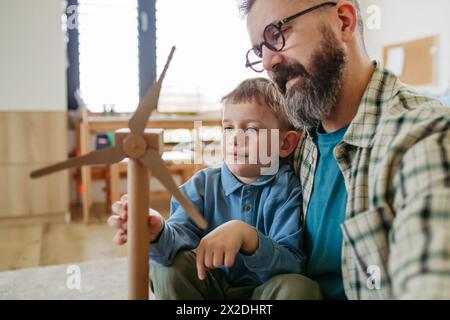 Sohn und Vater halten Windturbinenmodell. Concpet des nachhaltigen Lebensstils erneuerbarer Energien für die nächsten Generationen. Stockfoto
