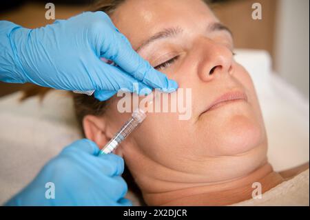 Weibliche Patientin, die in der Klinik kosmetische Gesichtsinjektion ins Gesicht bekommt Stockfoto