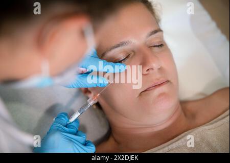 Gesichtsloser Kosmetiker, der dem Klienten eine Gesichtsverjüngung verabreicht Stockfoto
