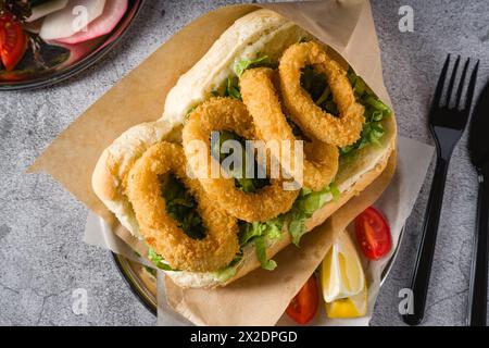 Frittierter Tintenfisch in Brot mit Gemüse an der Seite. Tintenfisch-Sandwich Stockfoto