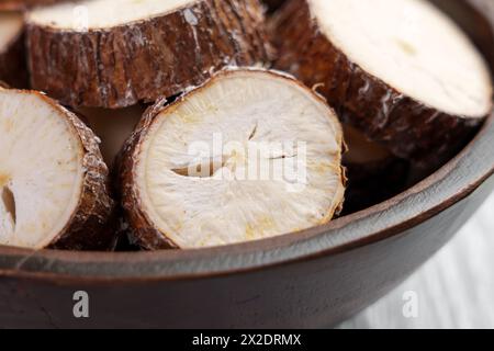 Rohe Yucca (Maniok) geschnittene Wurzel in Holzschüssel auf einem rustikalen Küchentisch Nahaufnahme. Drehung Stockfoto