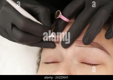 Microblading – halb-permanente Tätowiertechnik für die Augenbrauen, die eine Illusion von einer stärker definierten und volleren Augenbraue erzeugt. Der Künstler macht winziges h Stockfoto