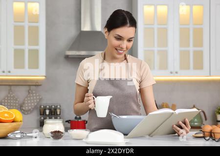 Junge Frau mit Rezeptbuch Kochen in der Küche Stockfoto