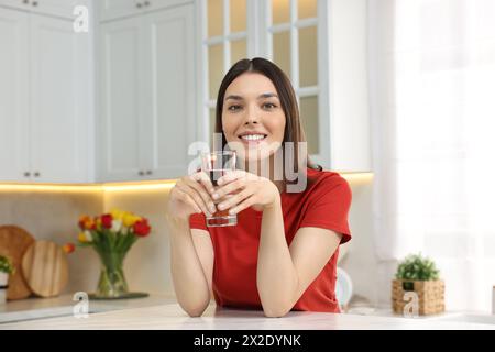 Eine junge Frau mit einem Glas Wasser in der Küche Stockfoto