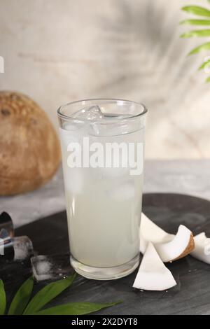 Ein Glas Kokoswasser, Eiswürfel und Nüsse auf dem Tisch Stockfoto