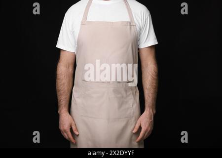 Mann mit Küchenschürze auf schwarzem Hintergrund, Nahaufnahme. Modell für Design Stockfoto