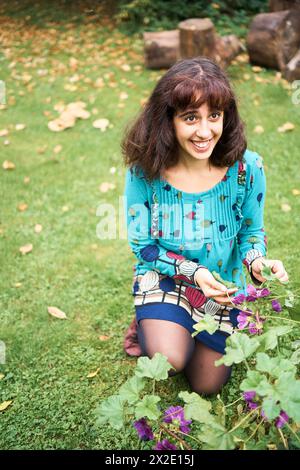 Mädchen in einem Kleid mit Ballons schaut Blumen im Garten an Stockfoto