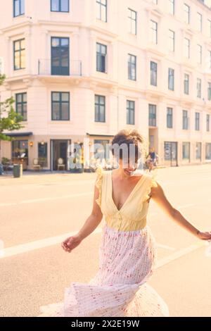 Ein Mädchen mit einem kurzen Haarschnitt in einem gelben Kleid auf den sonnendurchfluteten Straßen Kopenhagens Stockfoto