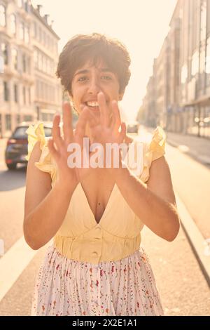 Ein Mädchen mit einem kurzen Haarschnitt in einem gelben Kleid auf den sonnendurchfluteten Straßen Kopenhagens Stockfoto