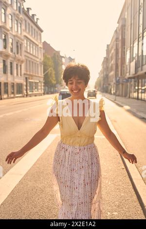 Ein Mädchen mit einem kurzen Haarschnitt in einem gelben Kleid auf den sonnendurchfluteten Straßen Kopenhagens Stockfoto