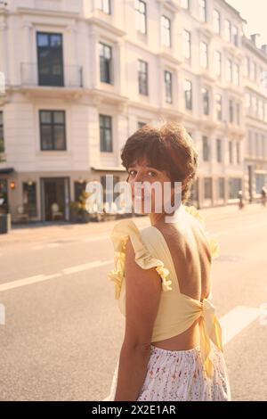 Ein Mädchen mit einem kurzen Haarschnitt in einem gelben Kleid auf den sonnendurchfluteten Straßen Kopenhagens Stockfoto