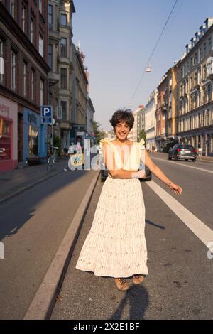 Ein Mädchen mit einem kurzen Haarschnitt in einem gelben Kleid auf den sonnendurchfluteten Straßen Kopenhagens Stockfoto