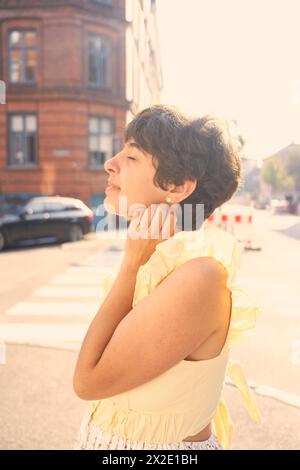 Ein Mädchen mit einem kurzen Haarschnitt in einem gelben Kleid auf den sonnendurchfluteten Straßen Kopenhagens Stockfoto