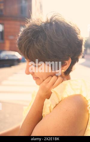 Ein Mädchen mit einem kurzen Haarschnitt in einem gelben Kleid auf den sonnendurchfluteten Straßen Kopenhagens Stockfoto