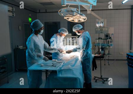 Wide shot von multiethnischen Berufschirurgen und -Schwestern bei einheitlich durchführender Herztransplantationschirurgie unter hellen Lampen mit medizinischer Hilfe Stockfoto