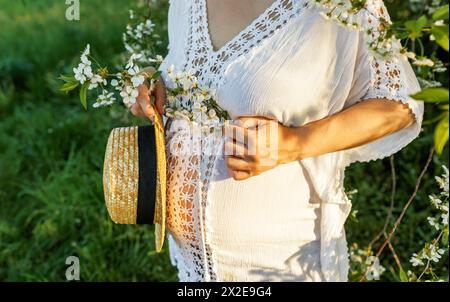 Der Bauch der schwangeren Frau in Nahaufnahme, mit blühenden Zweigen Stockfoto