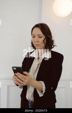 Gemischte Rassenfrauen in Business-Freizeitkleidung schaut sich das Telefon an Stockfoto