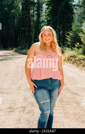 Ein wunderschönes Teenager-Mädchen in rosa Oberteil und Jeans, das auf dem Feldweg steht Stockfoto