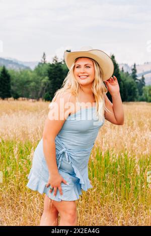 Porträt eines schönen Teenagermädchens in blauem Sommerkleid und Cowgirl-Hut Stockfoto