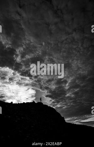 Einsamer Mensch, perfekt ausgerichtet auf den Bruch in den Wolken auf dem Berg Stockfoto