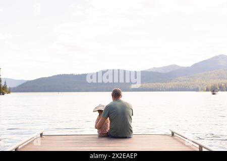 Dad und Tochter sitzen auf der Anlegestelle am See Stockfoto