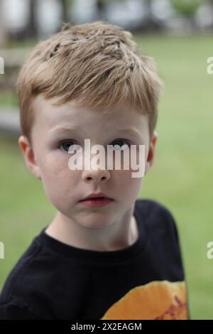 Nachdenklicher Junge in einem verspielten T-Shirt draußen Stockfoto