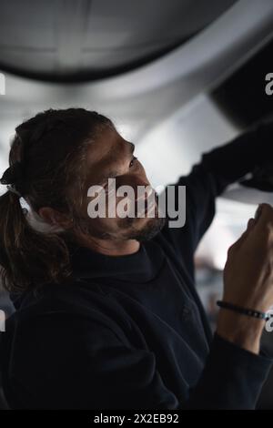 Ein Mann im Flugzeug legt sein Gepäck ins Regal. Stockfoto