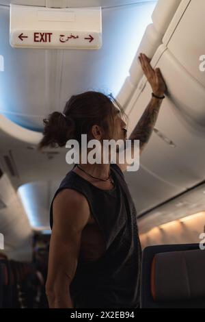 Ein Mann im Flugzeug legt sein Gepäck ins Regal. Stockfoto