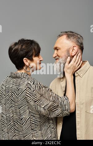 Ein Mann und eine Frau mittleren Alters in stilvoller Kleidung stehen anmutig nebeneinander in einem Studio-Setting. Stockfoto