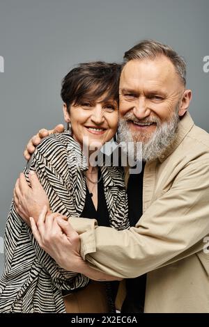 Ein Paar mittleren Alters in stilvoller Kleidung umarmen sich liebevoll in einem Studio. Stockfoto