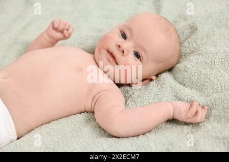 Süßes kleines Baby mit allergischer Rötung auf den Wangen, das auf hellgrüner Decke liegt Stockfoto