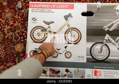 München, 8. April 2023: Vor dem Auspacken zeigt eine männliche Hand auf ein neues Puky-Lernrad, das noch auf dem Karton liegt und als Geschenk für ein Kleinkind gedacht ist Stockfoto