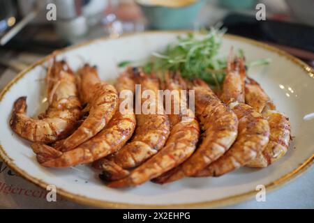 Langusten mit Spinatsoße auf einem weißen Teller auf einem Marmortisch mit einem Glas Weißwein. Hochwertige Fotos Stockfoto