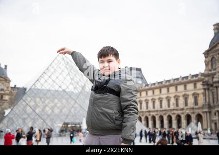 Touristenkind posiert vor dem Louvre Paris Stockfoto