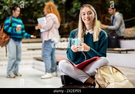 Porträt einer Studentin auf dem Campus mit Smartphone und Ohrhörern. Stockfoto