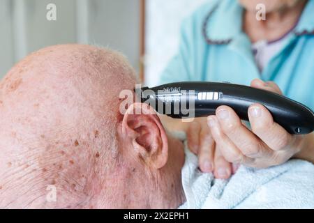 Nahaufnahme eines älteren Paares, das zu Hause Haare schneidet. Der ältere Mann ist kahl. Stockfoto