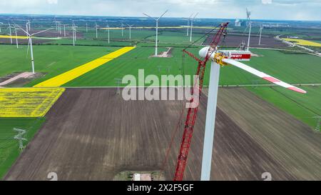 22. April 2024, Sachsen-Anhalt, Bad Lauchstädt: Die letzten Rotorblätter einer Windkraftanlage werden mit einem Kran im Energiepark Bad Lauchstädt installiert (Luftsicht mit Drohne). Der Energiepark Bad Lauchstädt in Mitteldeutschland ist derzeit das Pionierprojekt für Wasserstoff in Deutschland. In diesem Innovationsprojekt wird die Herstellung von grünem Wasserstoff aus Windkraft sowie dessen Speicherung, Transport, Vermarktung und Nutzung erstmals in Mitteldeutschland industriell getestet. Foto: Heiko Rebsch/dpa Stockfoto