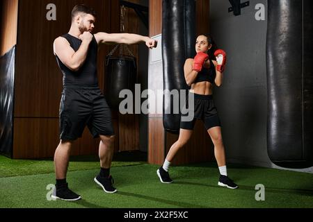 Ein männlicher Trainer führt eine brünette Sportlerin in aktiver Kleidung, während sie in einem Boxring in einem Fitnessstudio spärt. Stockfoto