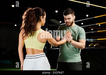 Ein männlicher Trainer unterrichtet einer Frau in einem Fitnessstudio Selbstverteidigungstechniken. Stockfoto