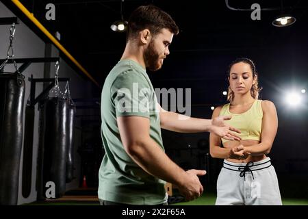 Ein männlicher Trainer bringt einer Frau in einem Fitnessstudio Techniken zur Selbstverteidigung bei und zeigt dabei Empowerment und Partnerschaft. Stockfoto