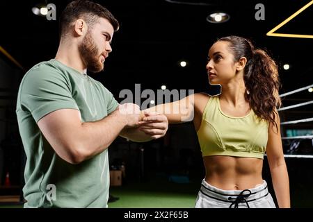 Ein männlicher Trainer unterrichtet einer Frau in einem Fitnessstudio Selbstverteidigungstechniken. Stockfoto