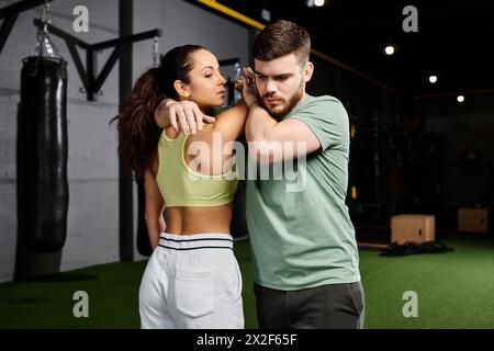 Ein männlicher Trainer bringt einer Frau im Fitnessstudio Techniken zur Selbstverteidigung bei und demonstriert Kraft und Einheit. Stockfoto