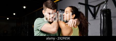 Ein männlicher Trainer unterrichtet einer Frau in einem Fitnessstudio Selbstverteidigungstechniken. Stockfoto