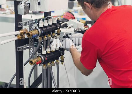 Installation des Sammelbehälters für die Warmwasserbodenheizung Klempnerarbeiten. Stockfoto