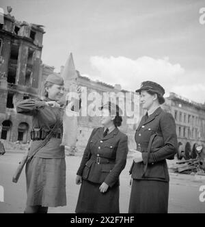 Foto der Sektionsoffiziere P. Hack und B. Hampson von der Frauenhilfsluftwaffe mit einem Verkehrslotsen der Roten Armee nahe dem Brandenburger Tor, Berlin, während der alliierten Besetzung Deutschlands, mit militärischem Personal und städtischem Umfeld. Stockfoto