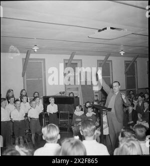 LERNEN DURCH SCHAUSPIELEREI: AUSBILDUNG DURCH THEATER FÜR EVAKUIERTE AN Einer „CAMP SCHOOL“, MARCHANT's HILL, HINDHEAD, SURREY, 1943 – an bestimmten Stellen des Stücks, das von Kindern an der Marchant's Hill School gespielt wird, singt der Schulchor traditionelle englische Lieder. Sie werden von Arthur Shuttleworth geleitet Stockfoto