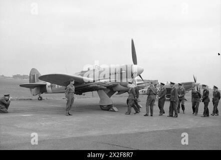 ROYAL AIR FORCE: 2. TAKTISCHE LUFTWAFFE, 1943-1945. - König George VI. Und sein Gefolge ranghoher RAF-Offiziere gehen zum Hawker Typhoon Mark IB, MN454 'HF-S', von der No. 183 Squadron RAF, während sie Flugzeuge und Ausrüstung inspizieren, die bei der bevorstehenden Invasion der Normandie in Northolt, Middlesex, eingesetzt werden. Die MN454 wurde von dem Kommandanten der 183 Squadron, dem Squadron Leader der Hon. F H Scarlett, geflogen. Hinter der Gruppe des Königs steht ein Supermarine Spitfire Mark IX der No. 222 Squadron RAF George VI, King, Royal Air Force, Maintenance Unit, 201, Royal Air Force, Royal Air Force Regiment, Sqdn, 183, Stockfoto