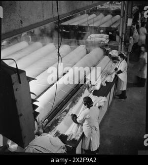 WÄSCHEREI IN KRIEGSZEITEN: DIE ARBEIT VON GLENIFFER WÄSCHEREI, CATFORD, LONDON, ENGLAND, UK, 1944: die Arbeiter der Gleniffer Laundry in Catford entfernen die Laken von der großen Trocknungs- und Bügelmaschine mit sechs Rollen. Die Blätter sind jetzt faltbar Stockfoto