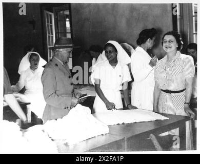 Lady Spinks vom Britischen Roten Kreuz überwacht freiwillige Arbeitsgruppen im Nahen Osten und interagiert mit einem jungen Helfer an einer Schneidebank, um humanitäre und Unterstützungsaktionen zu veranschaulichen. Stockfoto